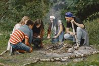 Young People Looking on Map by a Campfire 