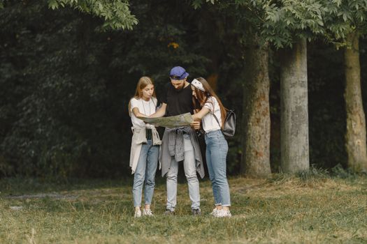 Three friends studying a map during a hiking trip in a lush forest.