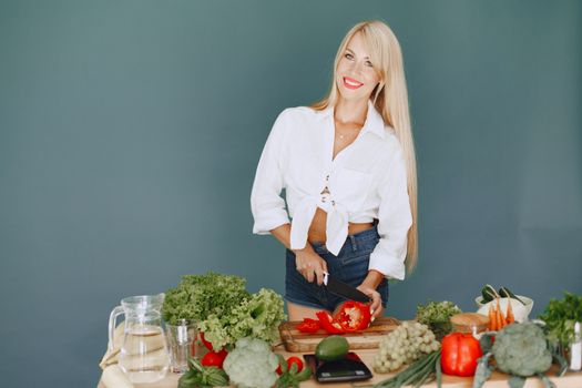 A smiling blonde woman chops vegetables, promoting healthy eating and lifestyle.