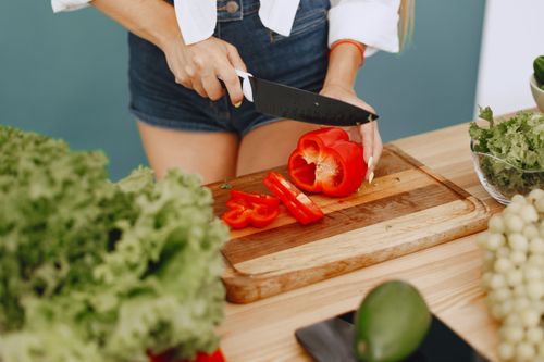Free Healthy cooking with fresh red pepper, lettuce, and avocado in a kitchen setting. Stock Photo