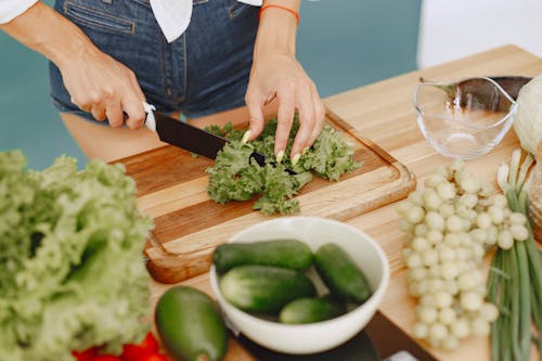 Woman Cutting Lettuce on Wooden Table