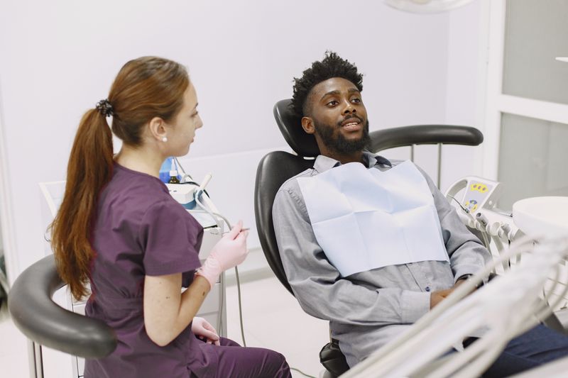 A Black man talks with a clinician during a clinic visit, the setting where a one-time hepatitis B screen and the vaccine are ordered.