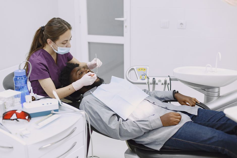 dry eye symptoms and treatments - Female dentist performing a dental checkup on a male patient in a modern clinic.