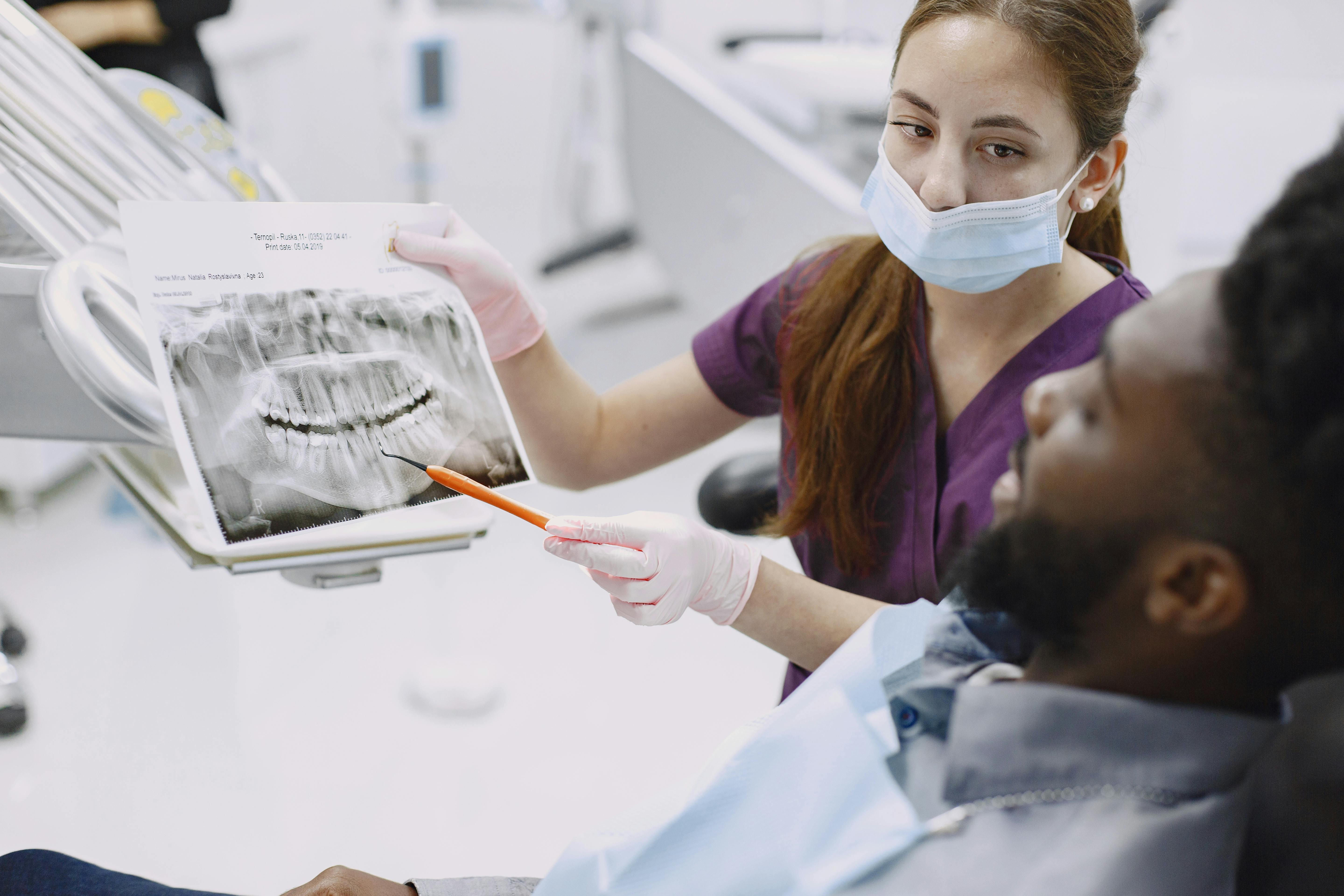 Female dentist explaining dental x-ray to a male patient in a modern clinic.