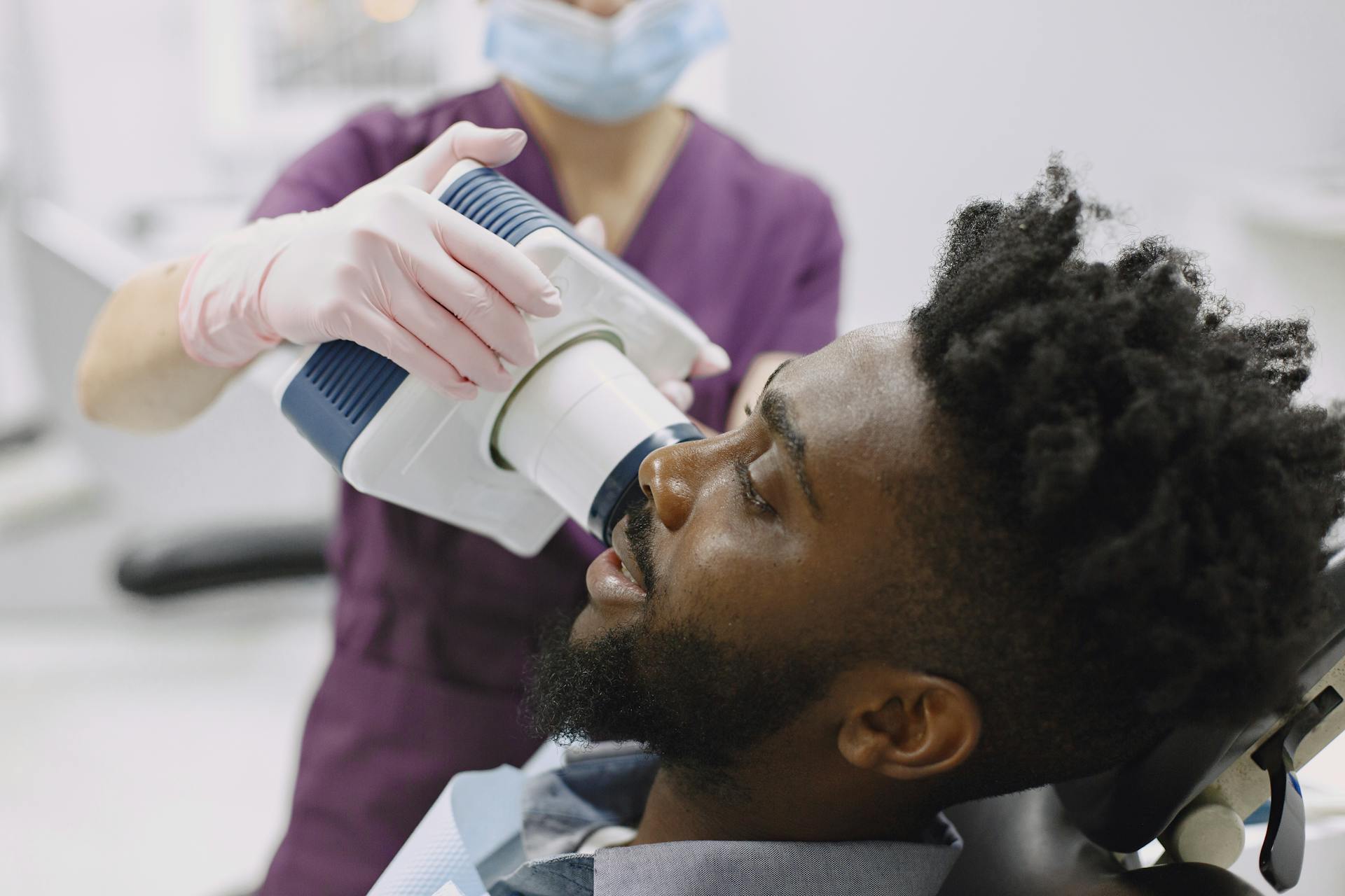 A patient receiving a dental x-ray from a dentist during a checkup session.