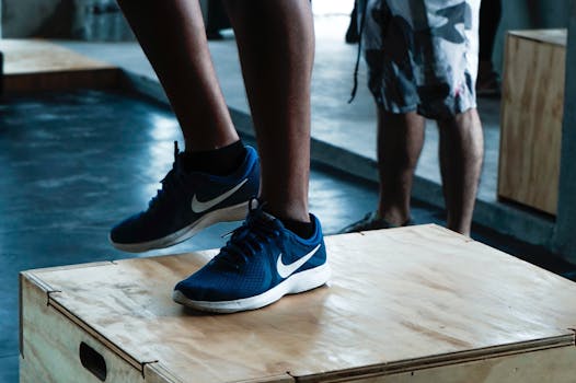 Close-up of blue Nike sneakers on a plyo box during workout in gym.