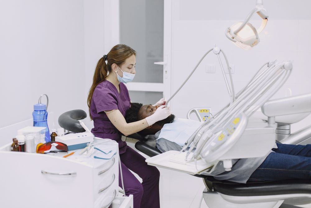 A dentist in purple scrubs working with a child in the chair