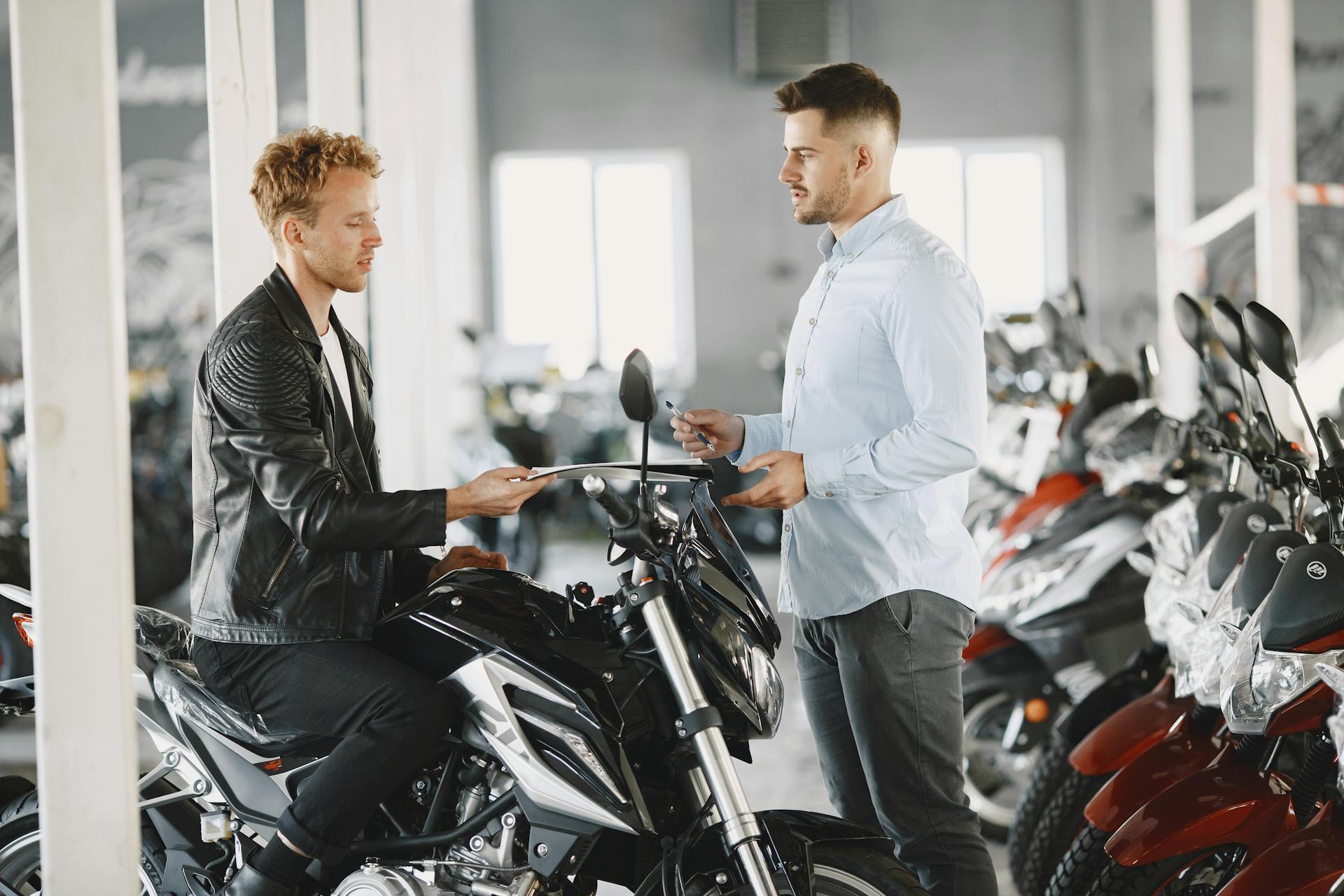 Two men in a motorcycle dealership discussing a potential motorcycle purchase.