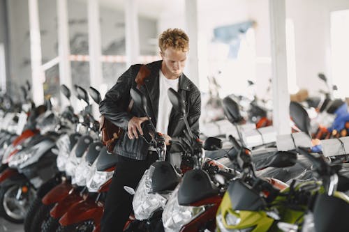 Free Man in Black Leather Jacket Looking at a Motorcycle Stock Photo