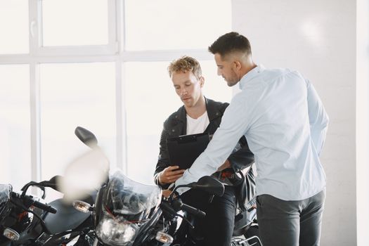 Two adults discussing motorcycle purchase inside dealership.