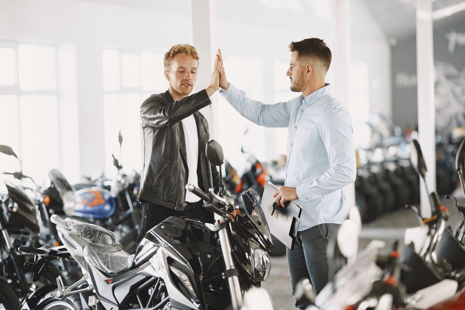 Deux personnes se félicitant lors de l'achat d'une moto dans une concession