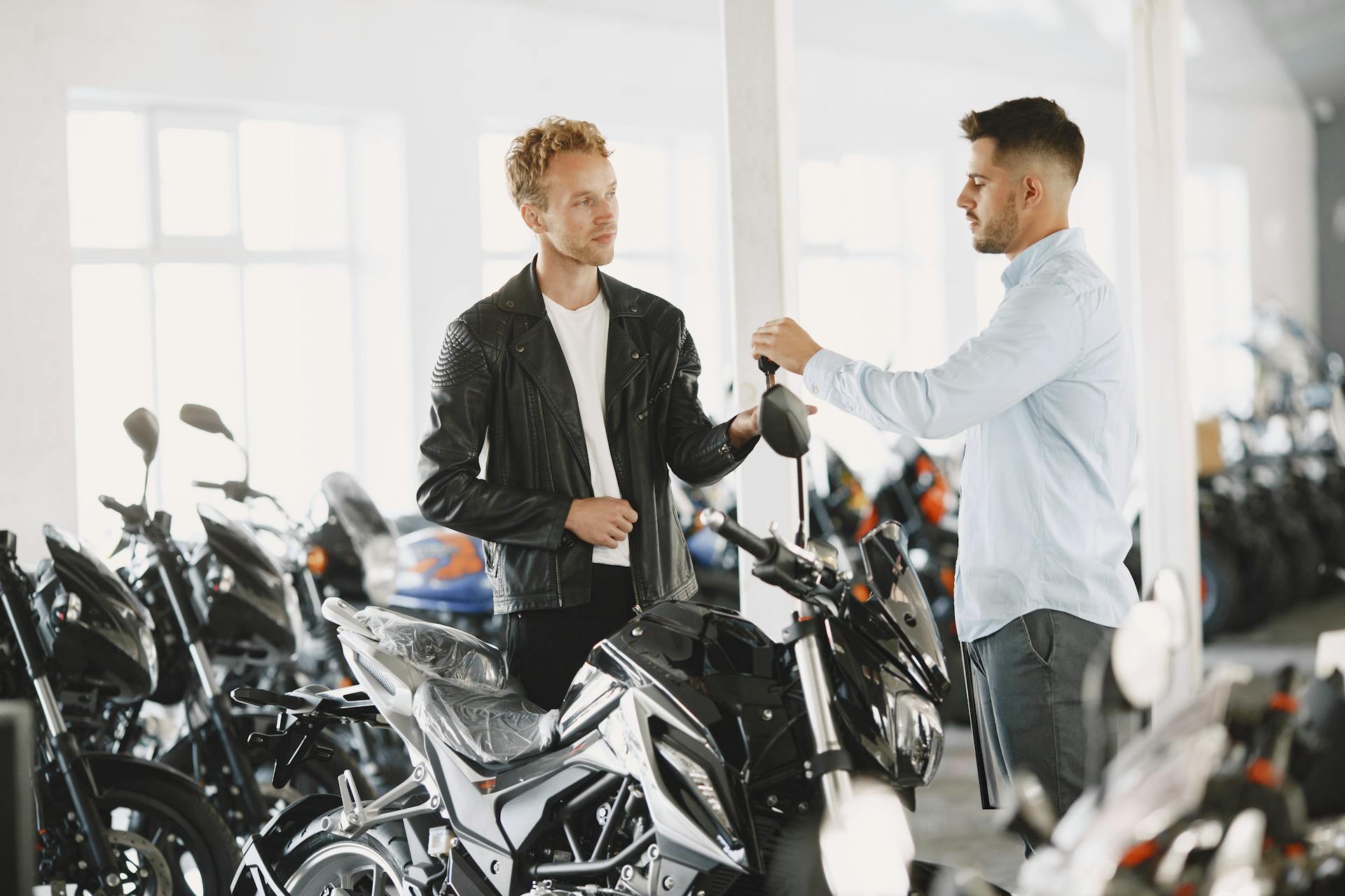 Two men engaged in conversation in a motorcycle showroom, highlighting customer interaction.