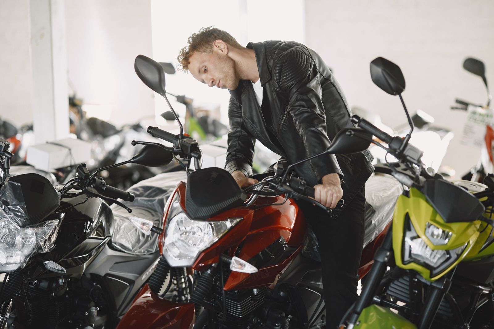 A customer looking over motorcycles inside a dealership showroom