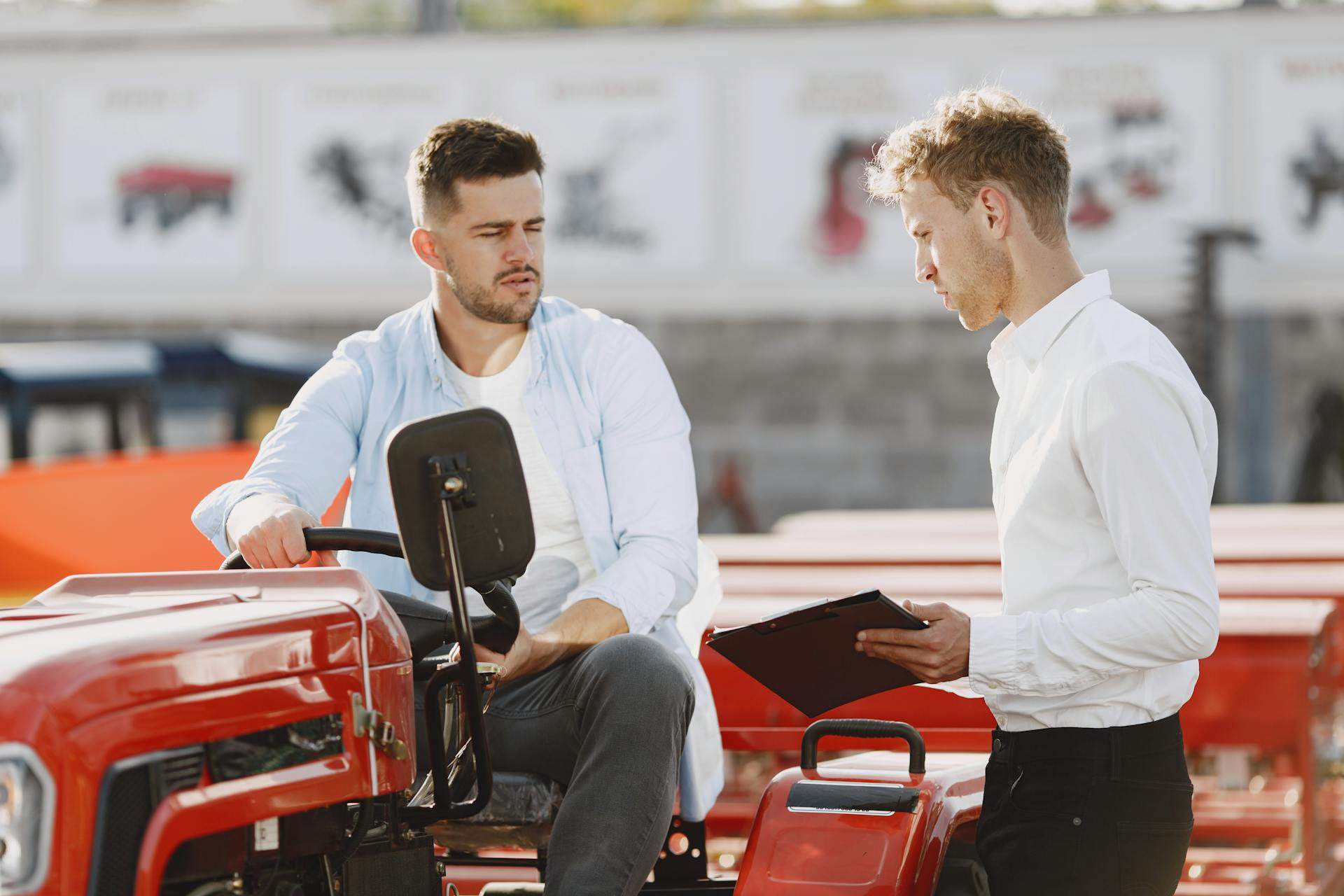 Two men discussing a deal at a tractor dealership, showcasing modern business interaction.