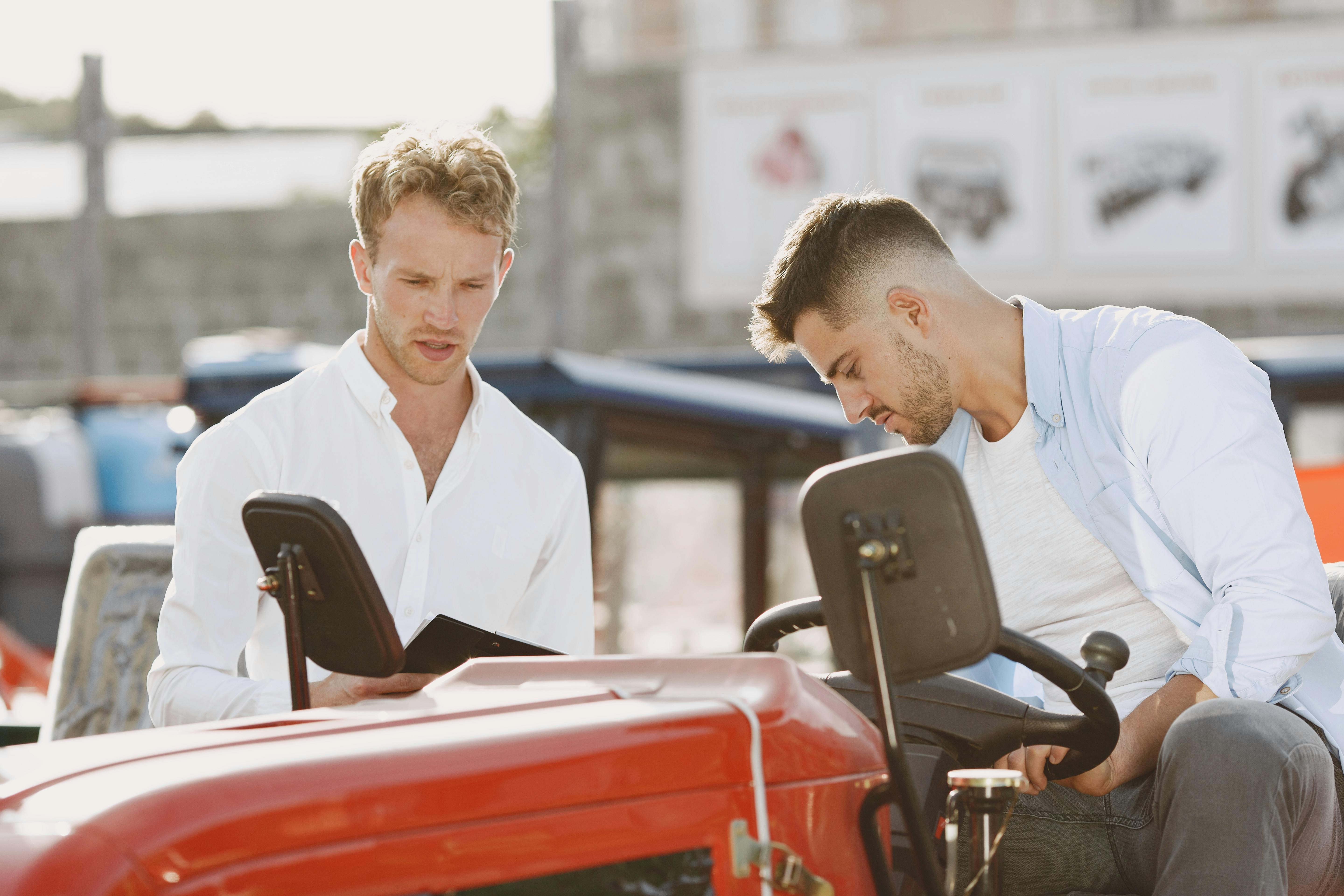 Two men engaging in a detailed discussion regarding a farm equipment purchase outdoors.