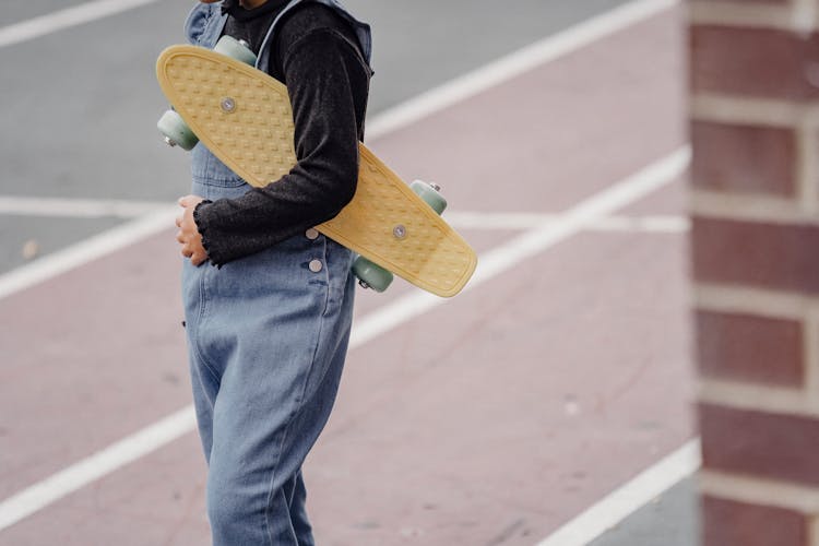 Crop Kid With Skateboard On Schoolyard