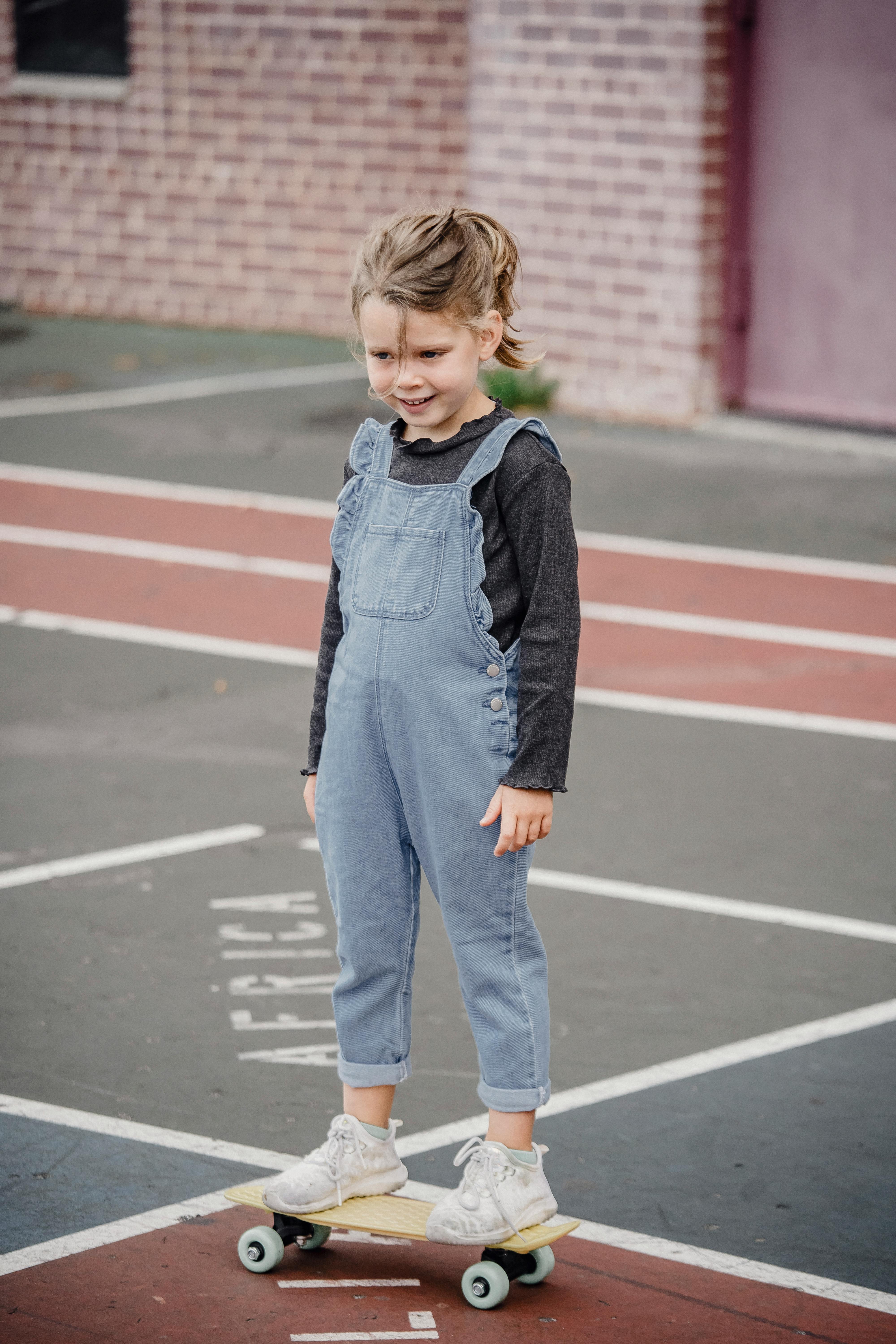 cheerful preschool girl standing on skateboard