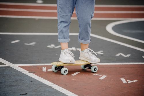 Free Crop faceless kid in jeans and sneakers riding skateboard on asphalt ground while training Stock Photo