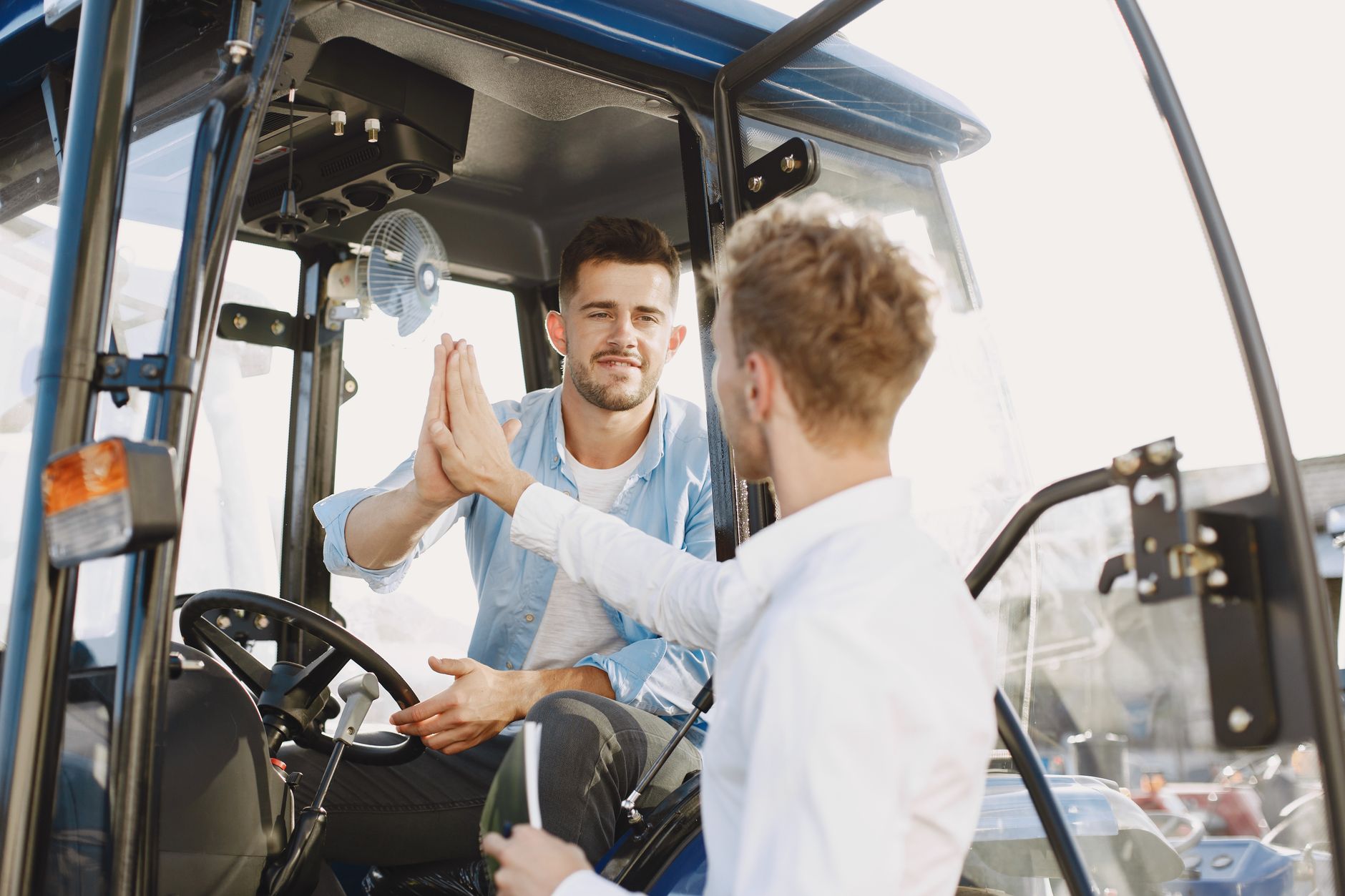 Two men exchanging a high five during a successful vehicle purchase, showcasing teamwork and agreement.