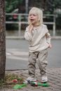 Full body adorable excited little girl in casual outfit standing near tree with toys and calling friend looking away