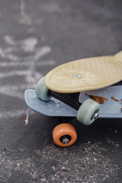 From above of colorful penny boards with rubber wheels placed on each other on asphalt surface