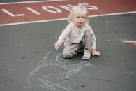 Adorable kid drawing on asphalt
