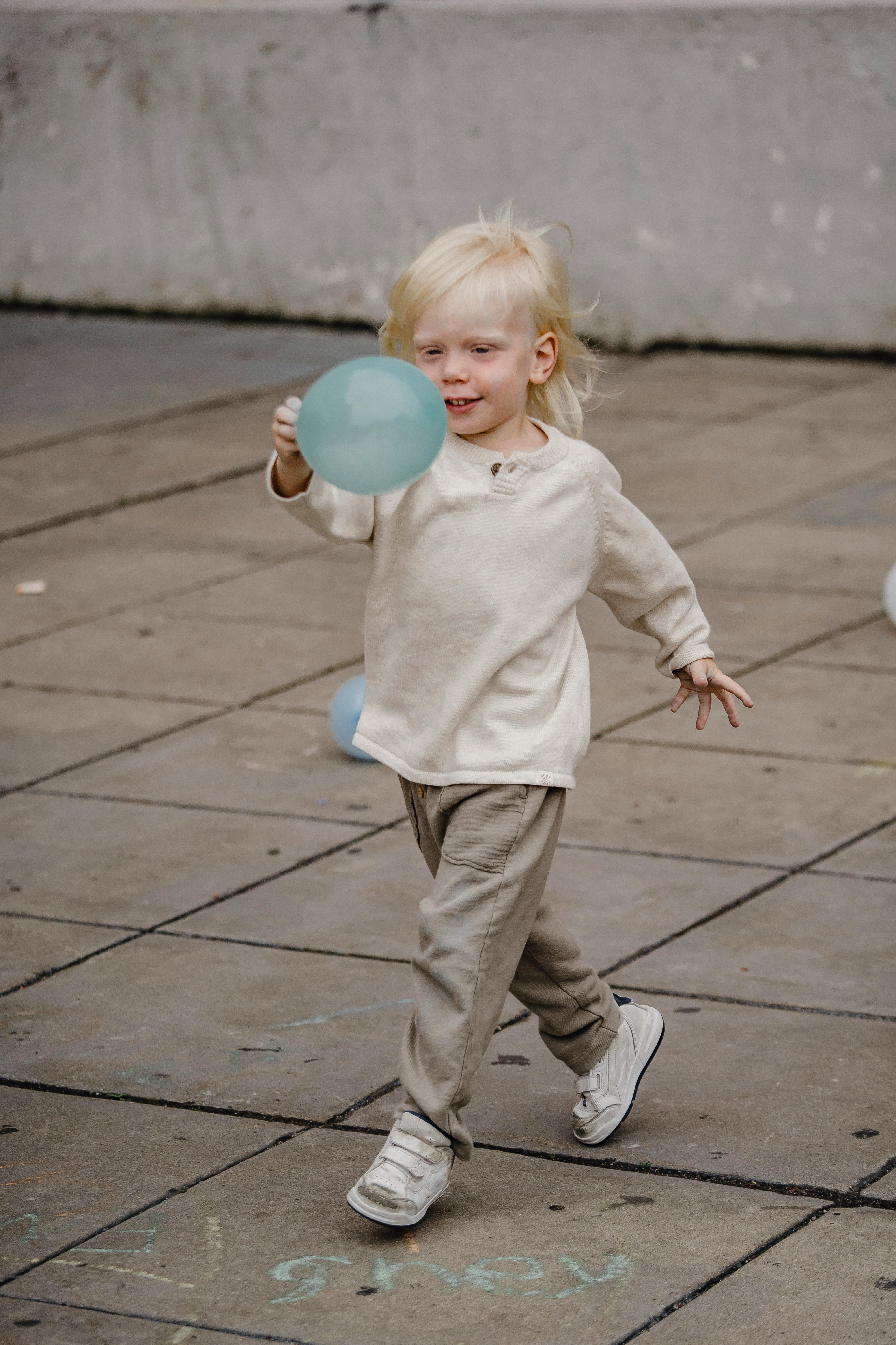 adorable boy with balloon walking on pavement