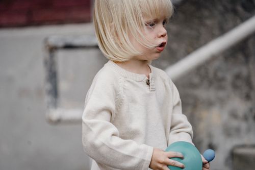 Free Crop focused blond child in casual soft clothes with balloons looking forward in daytime Stock Photo