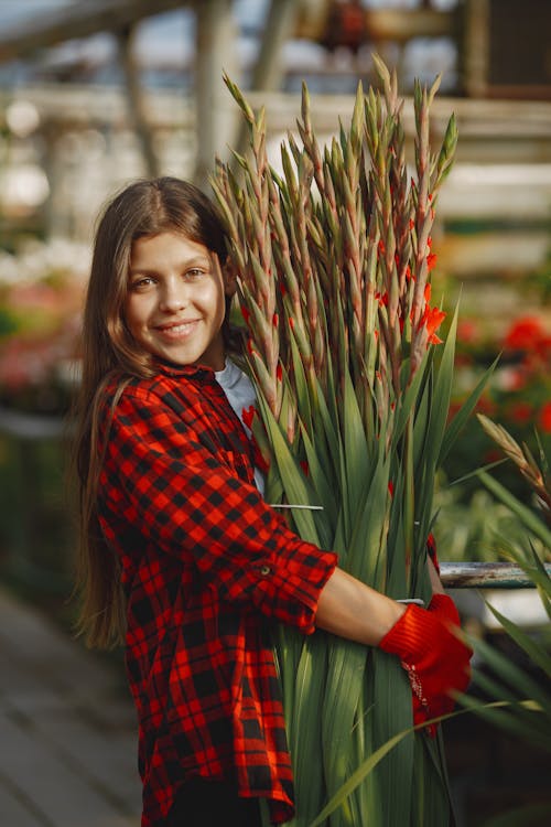 Smiling Girl in Red Plaid Shirt Holding Flowers