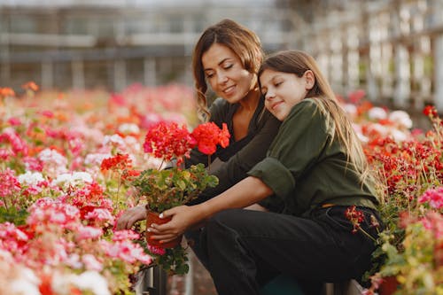 Mom and Daughter Looking at Blooming Red Flowers Together