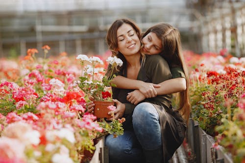 Daughter Hugging Her Mother Near Blooming Flowers