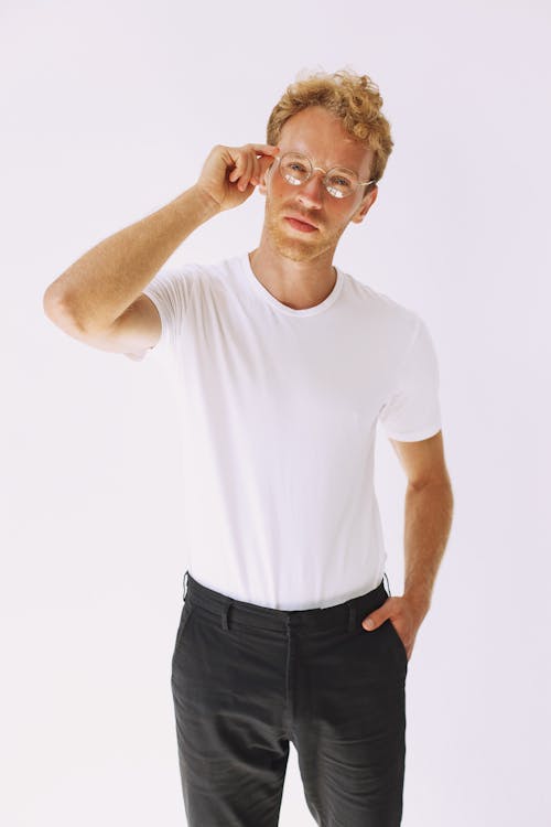 Man in White Crew Neck T-shirt and Black Pants Holding His Eyeglasses