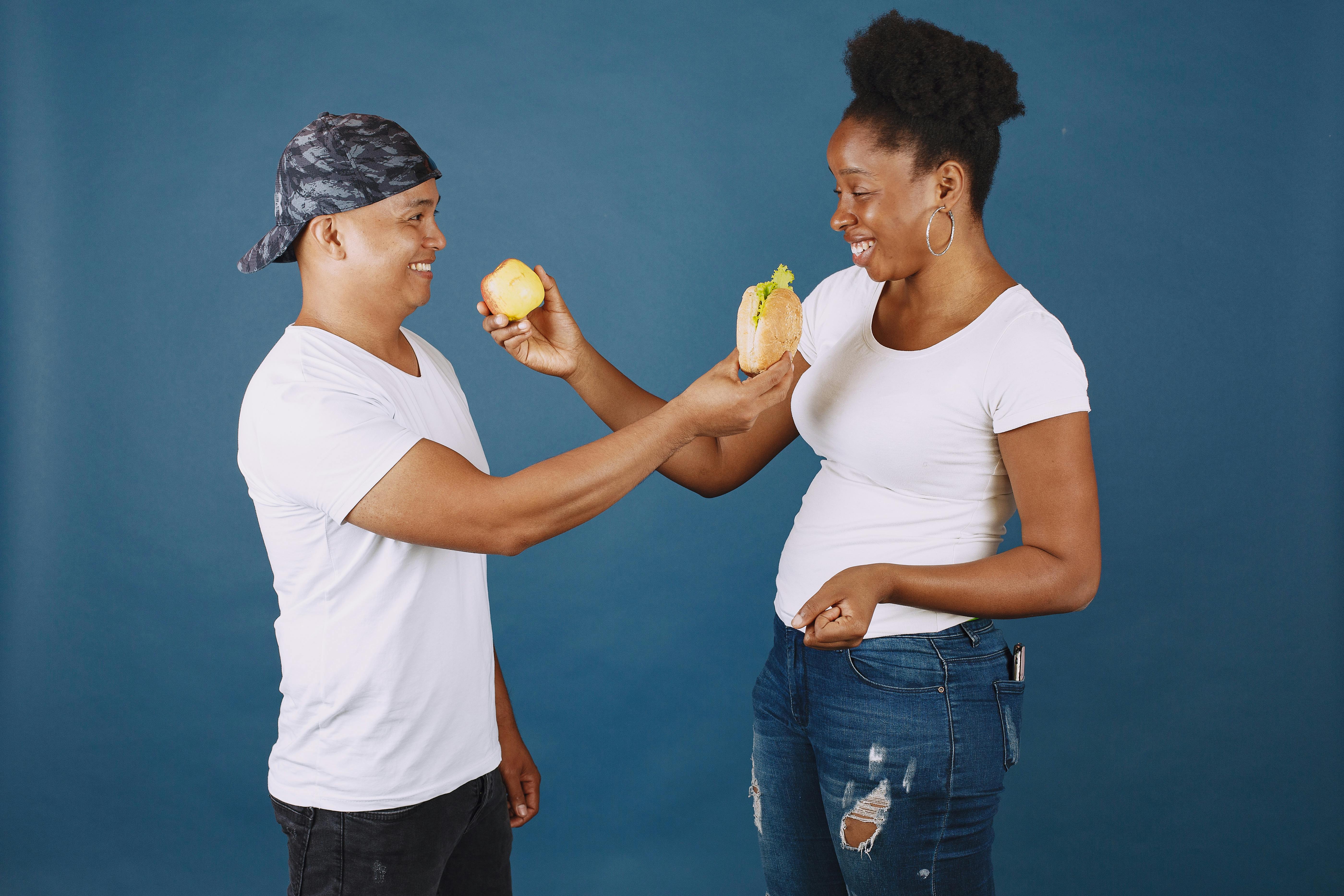 man and woman sharing an apple and sandwich