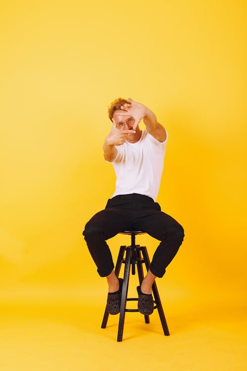 Man in White Shirt and Black Pants Sitting on a Stool