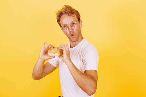 Free Man in White Shirt Holding a Delicious Burger Stock Photo