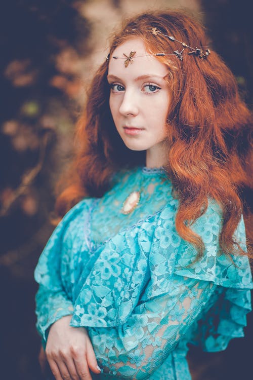 Young focused female with red hair in bright lace apparel of Renaissance era looking at camera
