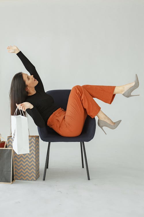 Happy Woman Sitting on a Chair Holding Shopping Bags 