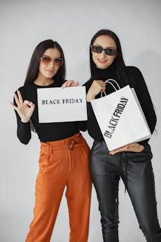 Two stylish women holding Black Friday shopping bags and sign.