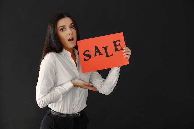 Surprised Woman Holding Sale Sign