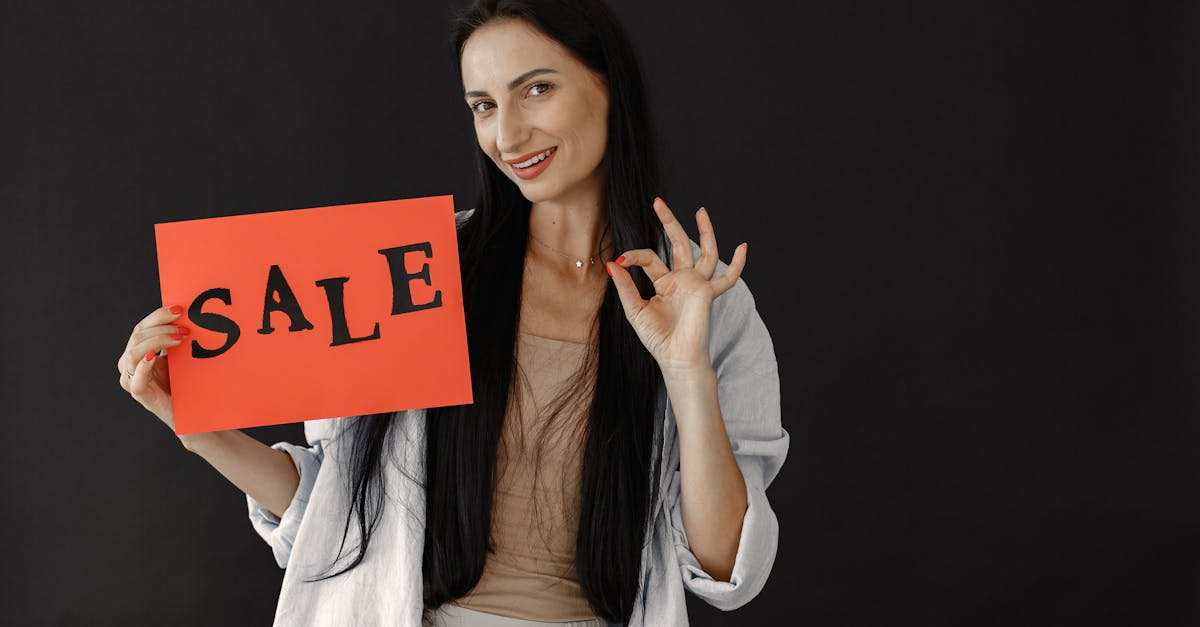 Brunette woman gesturing okay while holding a red sale sign on black background, perfect for consumerism and shopping themes.