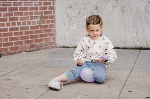 Free Shy girl playing with balloons on urban pavement Stock Photo