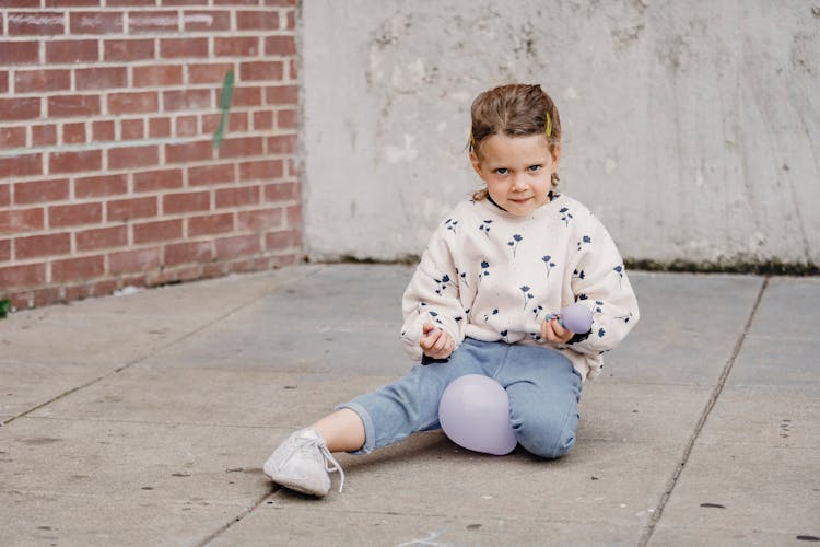 Shy Girl Playing With Balloons On Urban Pavement