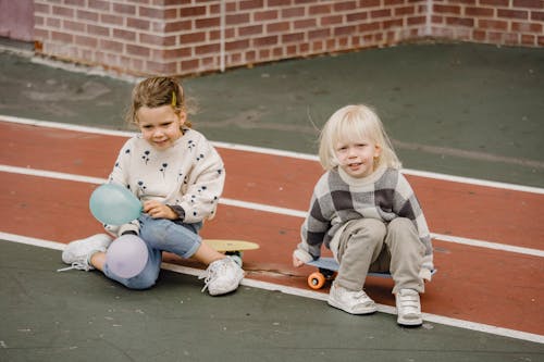 Smiling children with balloons resting on skateboards in town