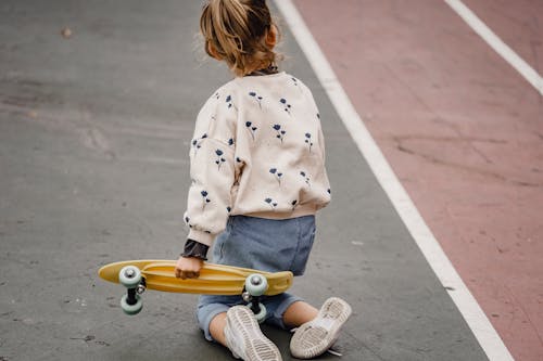 Crop girl with skateboard on sports ground