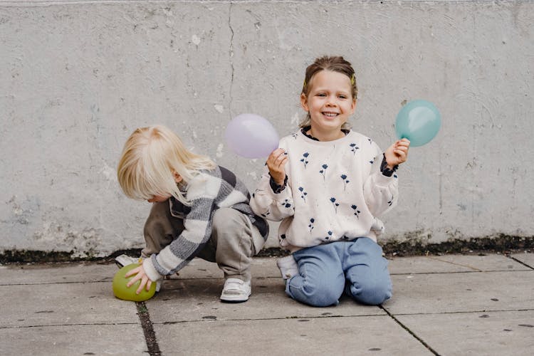 Smiling Girl With Balloons Near Unrecognizable Best Friend On Street