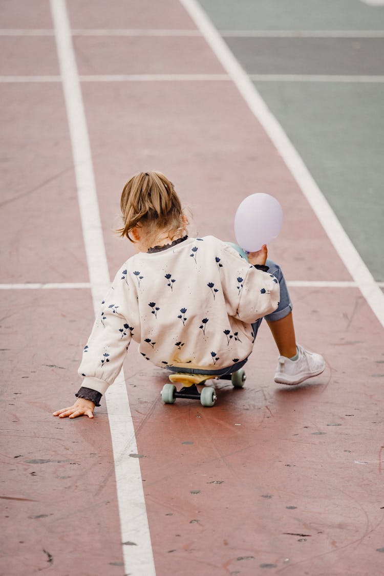 Faceless Kid Sitting On Skateboard Outside