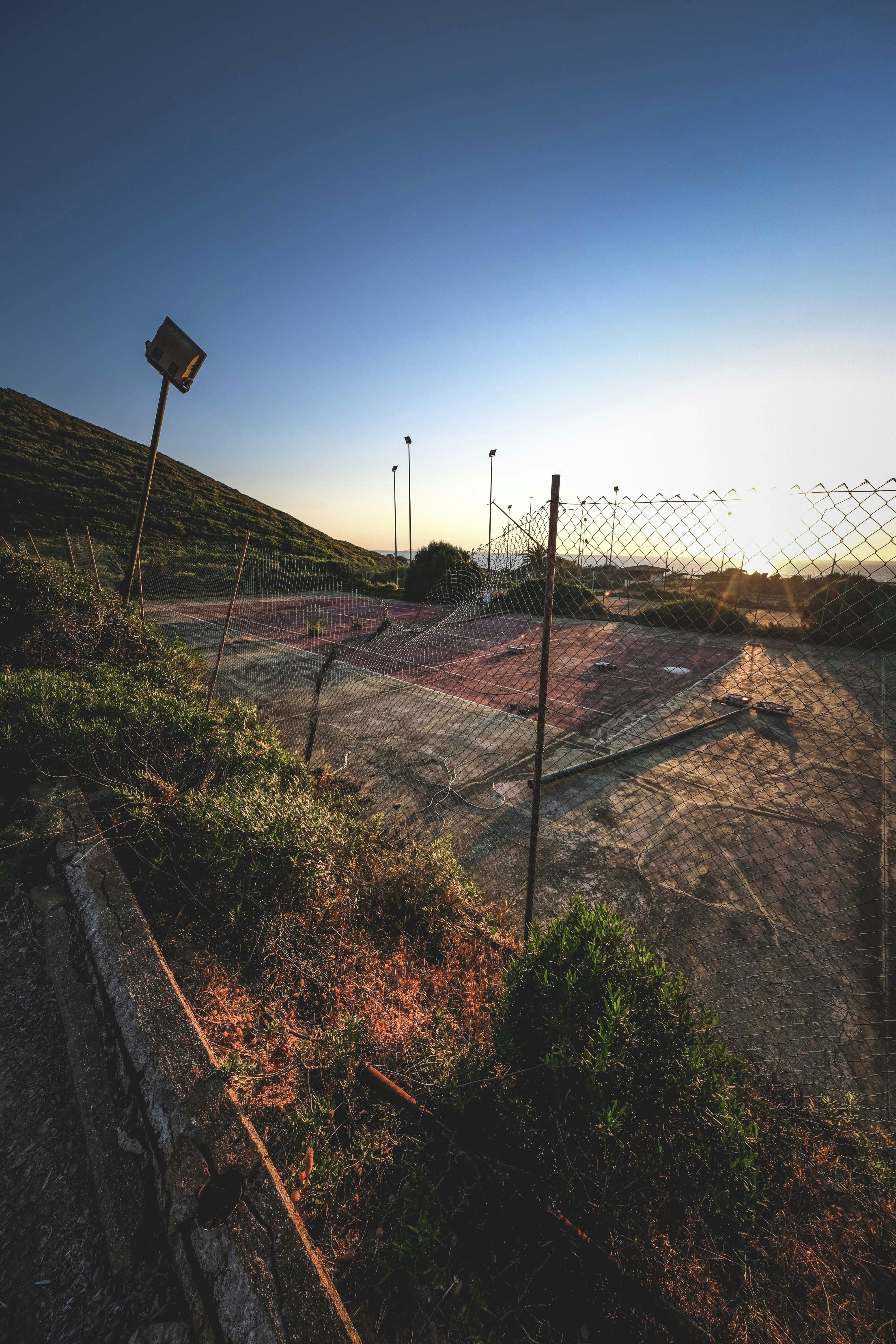 fenced sports court near hill on sunny day