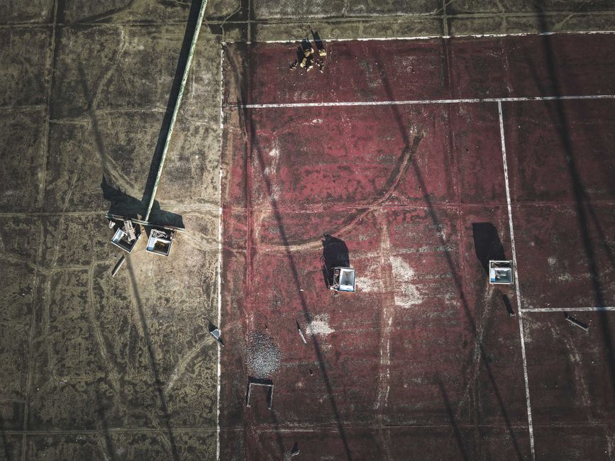 From above of broken streetlamps scattered on shabby old dirty sports ground on sunny day