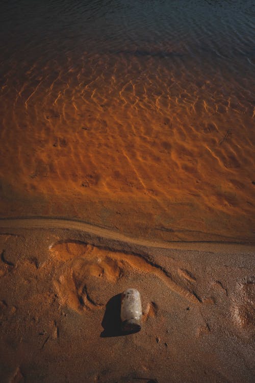 Sandy beach with plastic bottle