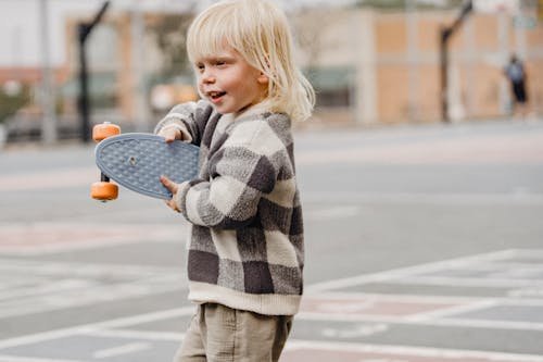 Happy little boy with penny board on street